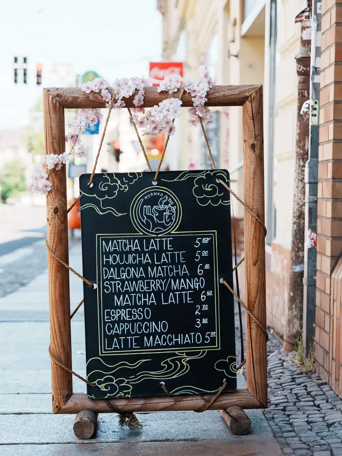 Aufsteller mit der handgeschriebenen Getränkekarte vor dem Café.